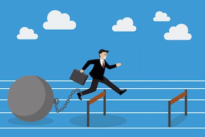 Businessman jumping over hurdle with the weight